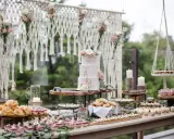 Un buffet de mariage bohème avec un gâteau à trois étages, des petits fours, des verrines et des pains. Une décoration macramé et florale complète cette idée repas mariage.