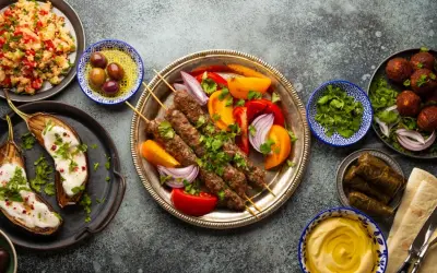 Un festin de plat méditerranéen : brochettes de viande, aubergines rôties, falafels, feuilles de vigne farcies, houmous et salade de couscous.