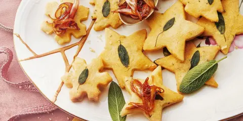 Biscuits en forme d'étoiles et de flocons, décorés de feuilles de sauge et d'oignons caramélisés. Un délice pour un repas de Noël pour enfant.