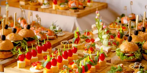 Buffet de petits fours variés : mini-burgers, toasts au saumon, brochettes de tomates et dés de fromage. Une belle idée pour une recette petit four réussie.