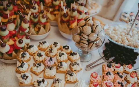 Délicieux assortiment de douceurs pour un brunch mariage : brochettes de fruits, mini gaufres à la crème, macarons et autres gourmandises.