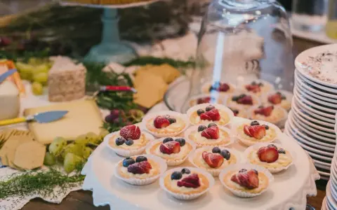 Un buffet de mariage avec des tartellettes aux fruits rouges, du fromage et des raisins. Une belle idée buffet mariage pour un événement gourmand.