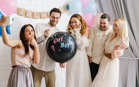 Groupe d'amis joyeux lors d'une annonce sexe du bébé. Un ballon noir avec "Girl? Boy?" au centre de la scène.