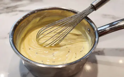 Préparation d'une crème onctueuse pour un flan Cyril Lignac, avec un fouet en action.