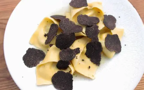 Délicieux raviolis frais garnis d'une généreuse quantité de lamelles de truffe noire. Un plat raffiné pour les amateurs de truffe.