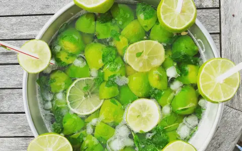 Un grand bol rempli de citrons verts, de menthe et de glaçons, prêt pour une recette mojito sans alcool 5 litres.