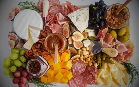 Plateau charcuterie et fromages : un buffet généreux avec jambon, saucisson, fromages variés, fruits, noix et confitures.