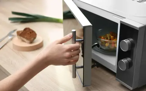 Main tenant ouvre son micro-ondes pour y placer un plat. La question est : peut-on mettre de l'inox au micro-onde ?