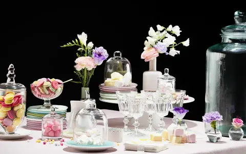 Buffet vin d'honneur fait maison : macarons colorés, meringues, guimauves et fleurs dans des vases.