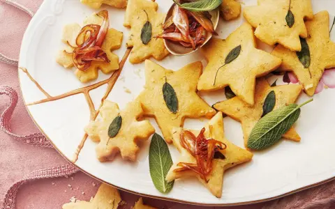 Biscuits en forme d'étoiles et de flocons, décorés de feuilles de sauge et d'oignons caramélisés. Un délice pour un repas de Noël pour enfant.
