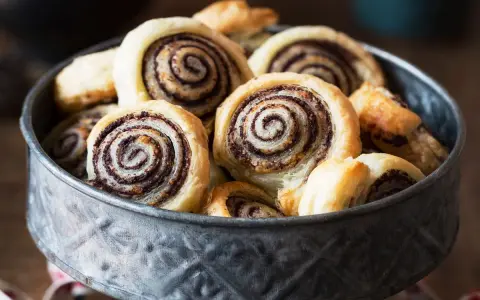 Un bol rempli de feuilletés tapenade, des roulés dorés à la pâte feuilletée croustillante et à la garniture sombre et savoureuse.
