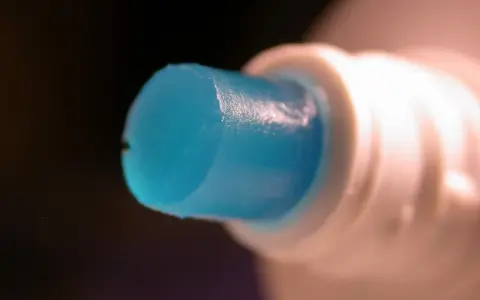 Goutte de dentifrice bleu sortant d'un tube blanc, parfaite pour polir l'aluminium.