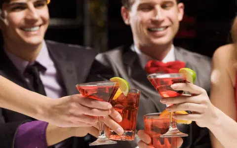 Des amis célèbrent avec des cocktails rouges, des rondelles de citron vert et d'orange. Une soirée de jeux du goût et de bonne humeur.