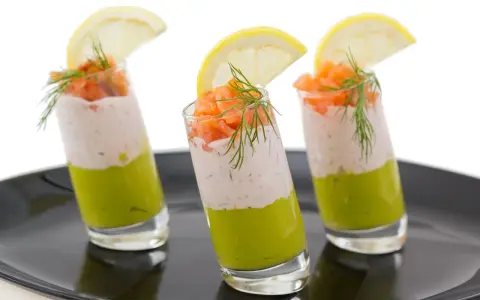 Trois verrines végétariennes colorées, garnies de saumon, d'une crème légère et d'une tranche de citron.
