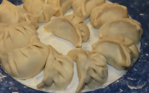 Assiette de ravioli pekinois crus, prêts à être cuisinés. La pâte est fine et plissée, prête à accueillir une garniture savoureuse.