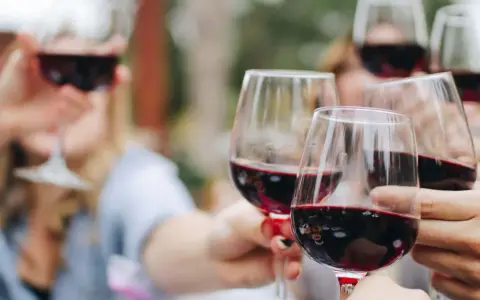Des verres de vin rouge levés en toast. Pour 40 personnes, combien de bouteille de vin prévoir ? Environ 15 à 20 bouteilles.