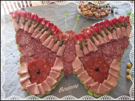 Un papillon charcuterie, composé de jambon, saucisson, cornichons et radis, prêt à émerveiller vos invités.