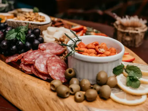 Plateau gourmand avec raisins, saucisson, olives, cacahuètes épicées et fruits. Un vrai menu campagnard !