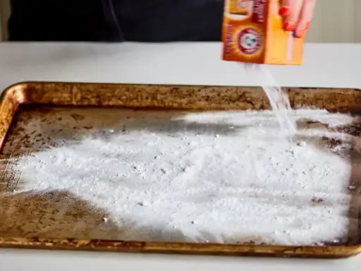 Saupoudrer du bicarbonate de soude sur une plaque de four brûlée. Une astuce pour savoir comment enlever du brûlé sur une plaque de four.