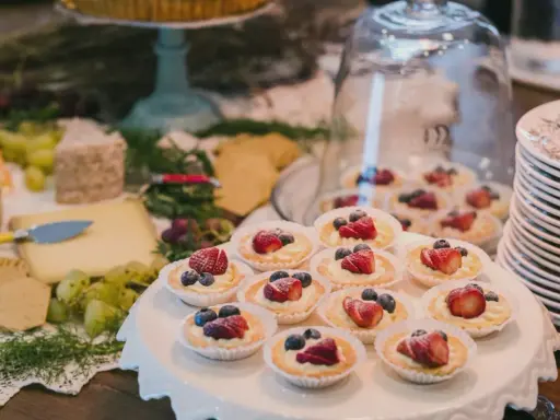Un buffet de mariage avec des tartellettes aux fruits rouges, du fromage et des raisins. Une belle idée buffet mariage pour un événement gourmand.