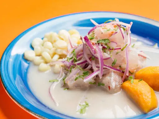 Ceviche frais baignant dans un leche de tigre crémeux, garni d'oignons rouges, de coriandre, de maïs et de patate douce.