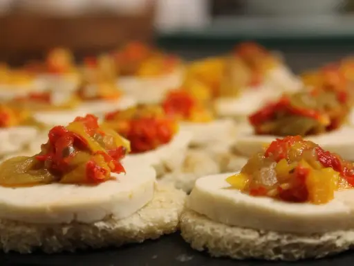 Petits toasts pour l'apéro, garnis de fromage blanc et d'une préparation colorée de poivrons et oignons.