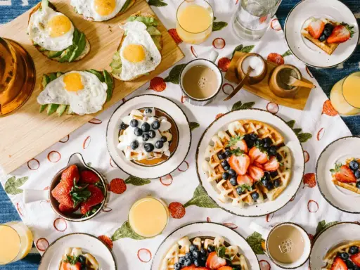 Un petit déjeuner continental ou américain avec des toasts à l'avocat et aux œufs, des gaufres aux fruits rouges et des jus.