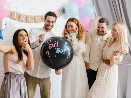 Groupe d'amis joyeux lors d'une annonce sexe du bébé. Un ballon noir avec "Girl? Boy?" au centre de la scène.