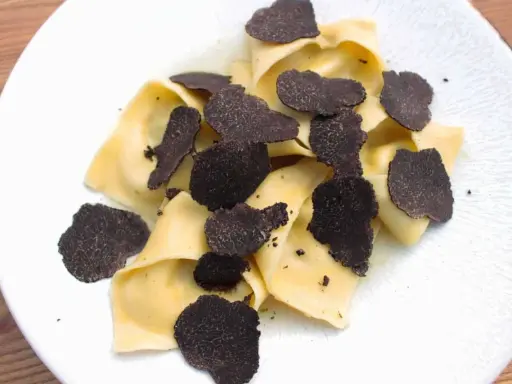 Délicieux raviolis frais garnis d'une généreuse quantité de lamelles de truffe noire. Un plat raffiné pour les amateurs de truffe.