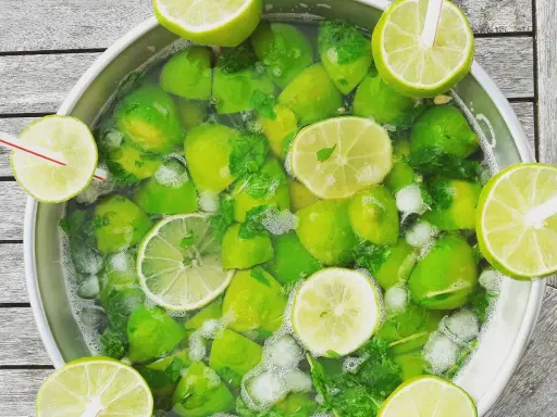 Un grand bol rempli de citrons verts, de menthe et de glaçons, prêt pour une recette mojito sans alcool 5 litres.