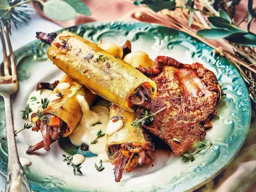 Un délicieux repas d'anniversaire léger : cannellonis farcis à la viande et légumes, accompagnés d'une sauce crémeuse et d'une tranche de viande croustillante.