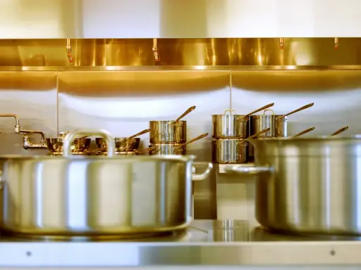 Une cuisine professionnelle avec des casseroles en acier inox 18/10 étincelantes. Des robinets chromés et des gicleurs de sécurité complètent l'ensemble.