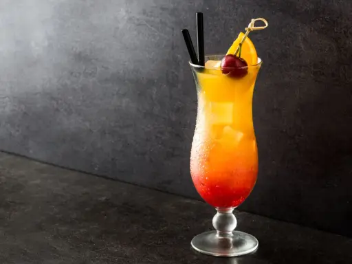 Cocktail Sex on the Beach recette 5l, dégradé rouge-orange, garni d'une cerise et d'une tranche d'orange.