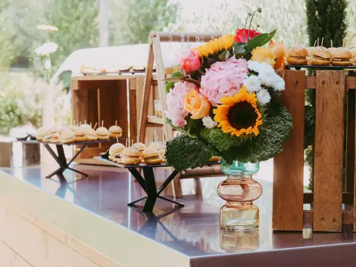 Un buffet de mini-burgers et un bouquet coloré, une belle idée apéro mariage en plein air.