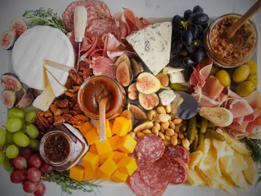 Plateau charcuterie et fromages : un buffet généreux avec jambon, saucisson, fromages variés, fruits, noix et confitures.