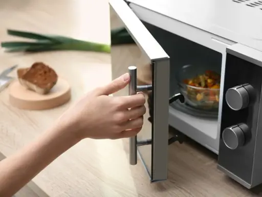 Main tenant ouvre son micro-ondes pour y placer un plat. La question est : peut-on mettre de l'inox au micro-onde ?