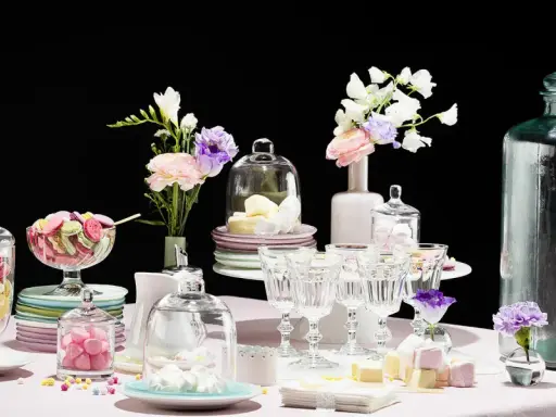 Buffet vin d'honneur fait maison : macarons colorés, meringues, guimauves et fleurs dans des vases.