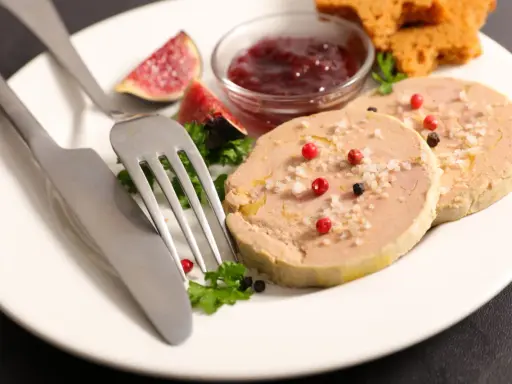 Assiette de foie gras, figues, confiture de fruits rouges et toasts. Une présentation raffinée pour un délice.