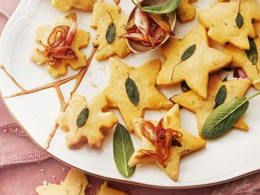 Biscuits en forme d'étoiles et de flocons, décorés de feuilles de sauge et d'oignons caramélisés. Un délice pour un repas de Noël pour enfant.