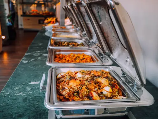 Buffet de plats chauds, idéal pour un pique-nique gourmand. Des mets variés dans des chafing dishes brillants.