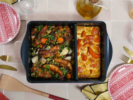 Comment savoir si un plat va au four ? Ce plat divisé présente du poulet rôti aux légumes d'un côté et un gratin de tomates de l'autre.