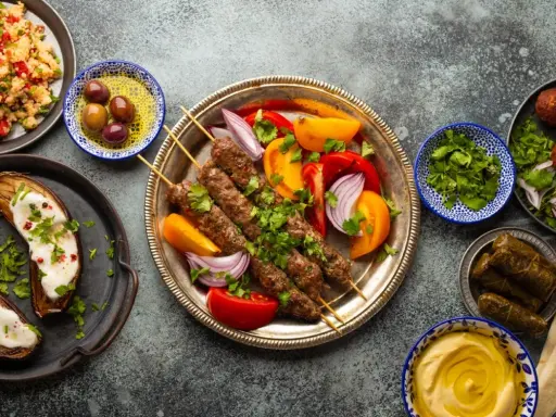 Un festin de plat méditerranéen : brochettes de viande, aubergines rôties, falafels, feuilles de vigne farcies, houmous et salade de couscous.