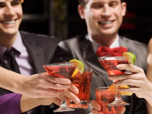 Des amis célèbrent avec des cocktails rouges, des rondelles de citron vert et d'orange. Une soirée de jeux du goût et de bonne humeur.
