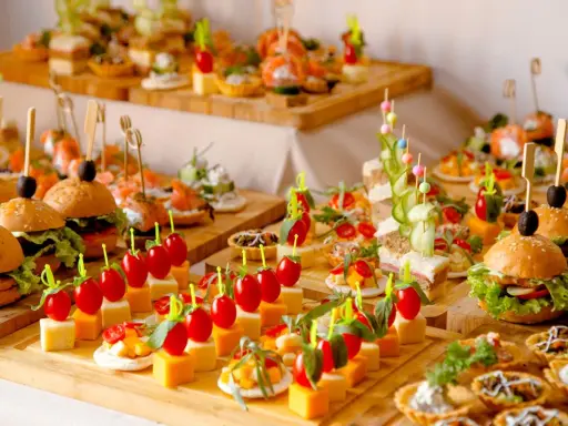 Buffet de petits fours variés : mini-burgers, toasts au saumon, brochettes de tomates et dés de fromage. Une belle idée pour une recette petit four réussie.