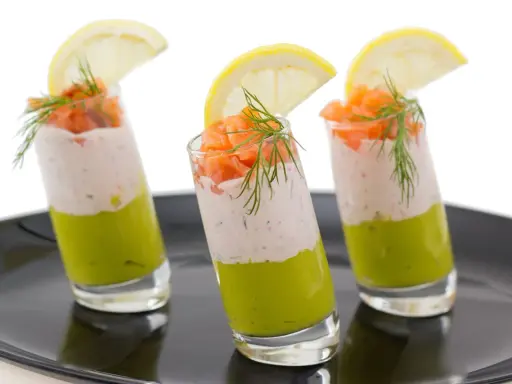 Trois verrines végétariennes colorées, garnies de saumon, d'une crème légère et d'une tranche de citron.