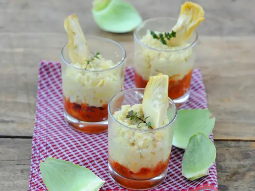 Trois verrines artichaut, garnies d'une purée crémeuse et d'une touche de sauce tomate, sur un fond de bois rustique.
