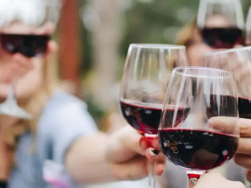 Des verres de vin rouge levés en toast. Pour 40 personnes, combien de bouteille de vin prévoir ? Environ 15 à 20 bouteilles.