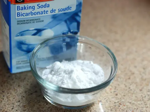 Un bol de bicarbonate de soude à côté de sa boîte. Un ingrédient polyvalent, utile pour le nettoyage et la cuisine, et même pour des expériences scientifiques impliquant de l'aluminium.