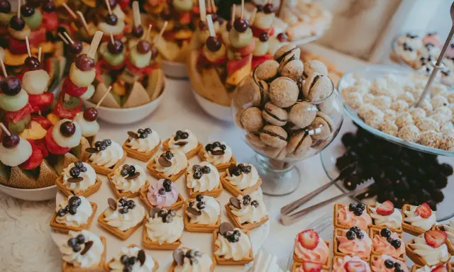 Délicieux assortiment de douceurs pour un brunch mariage : brochettes de fruits, mini gaufres à la crème, macarons et autres gourmandises.