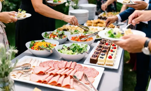 Un buffet garni pour un plat soiree : salades fraîches, charcuteries, et petits gâteaux décorés. Les invités se servent.
